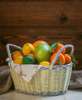 citrus fruits in a wicker basket on a wooden background