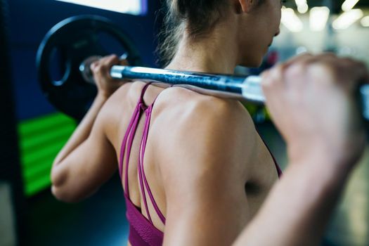 Athletic woman in gym lifting weights at the gym. Fitness concept.