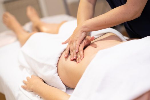 Woman receiving a belly massage in a physiotherapy center. Female patient is receiving treatment by professional osteopathy therapist.