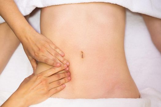 Top view of hands massaging female abdomen.Therapist applying pressure on belly