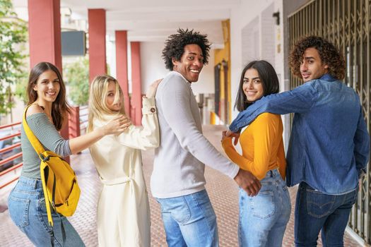 Rear view of multi-ethnic group of friends walking together on the street while chatting and having fun.