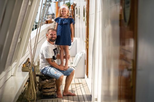 A little girl sits in the arms of a man on the deck of a large sailing ship in the city of Klaipeda, Lithuania