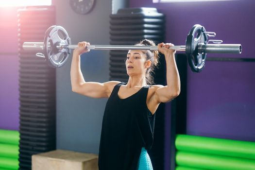 Athletic woman in gym lifting weights at the gym. Fitness concept.