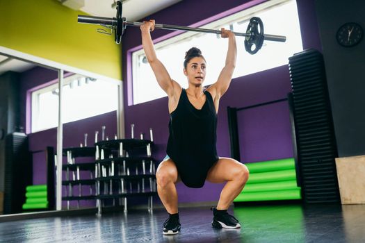 Athletic woman in gym lifting weights at the gym. Fitness concept.