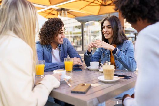 Multi-ethnic group of friends having a drink together in an outdoor bar. Young people having fun.