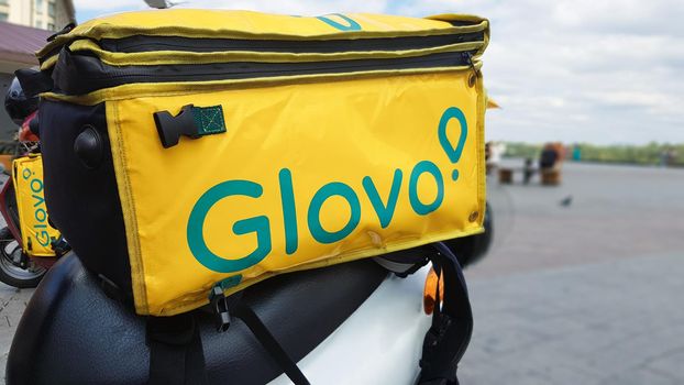 Ukraine, Kiev - August 29, 2020. Parked moped with yellow bag with Glovo logo near McDonald's close-up. Courier service that delivers goods ordered through a mobile application. Editorial photography