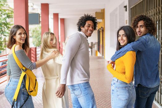 Rear view of multi-ethnic group of friends walking together on the street while chatting and having fun.