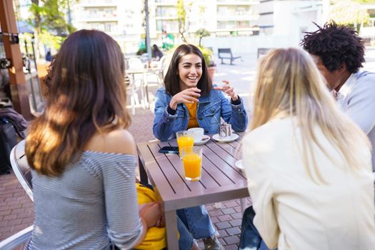 Multi-ethnic group of friends having a drink together in an outdoor bar. Young people having fun.