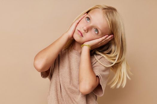 Beautiful little girl in a beige t-shirt posing studio. High quality photo