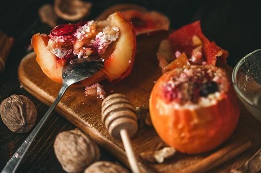 baked apples with cottage cheese with berries and nuts, topped with honey and sprinkled with cinnamon. on a wooden surface in a rustic style