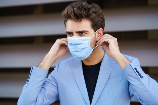 Caucasian businessman putting on a surgical mask to protect against the coronavirus.