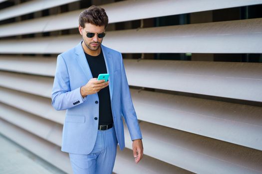 Young man walking down the street using his smartphone with a serious expression