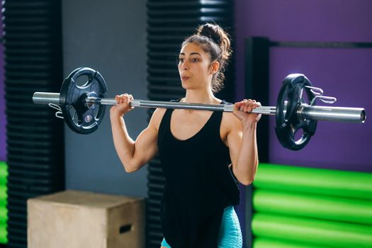 Athletic woman in gym lifting weights at the gym. Fitness concept.