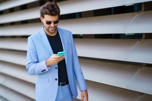 Young man walking down the street using his smartphone with a happy expression