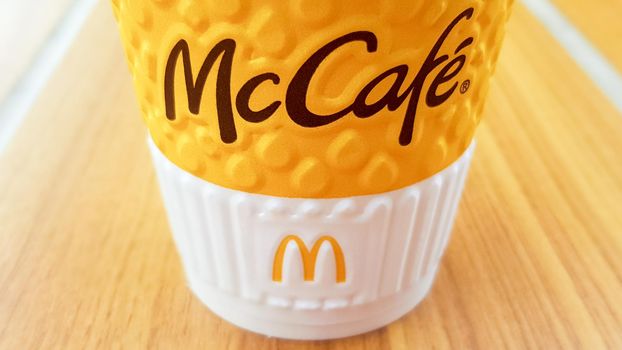 McCafe menu at McDonalds restaurant. Yellow cup of coffee on the table outdoors close-up. Breakfast, coffee time. Ukraine, Kiev - September 6, 2019