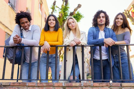 Multiracial group of young people talking together in the street. Students socializing.