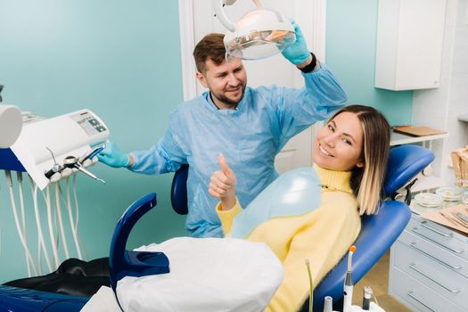 Beautiful girl patient shows the class with her hand while sitting in the Dentist's chair.