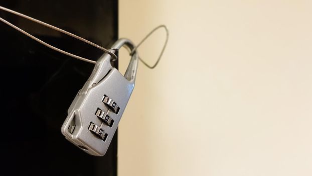 Close-up small combination lock closes electrical panel with black glass cover in office building corridor.