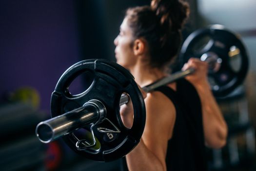 Athletic woman in gym lifting weights at the gym. Fitness concept.