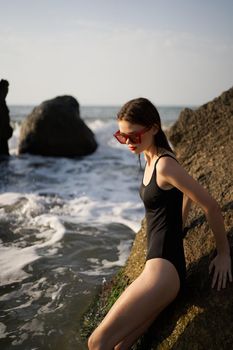 woman in swimsuit sunglasses ocean rocks posing. High quality photo