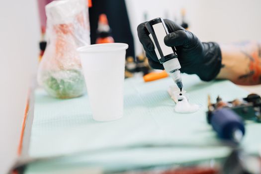 Female tattooist preparing the dyes she's going to work with using black ink. Tattoo concept.