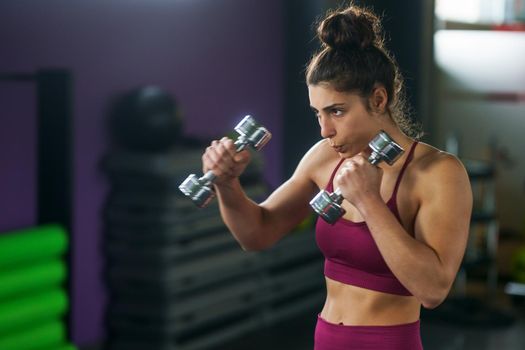 Sporty woman punching and boxing with dumbbells. Hard exercising and training at the gym. Fitness concept.