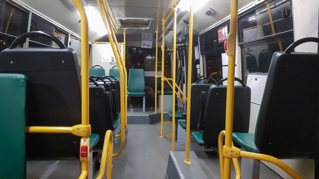 An empty bus is equipped with handrails for holding it on the inside. Modern land-based suburban and urban public passenger transport in the city. Passenger seats