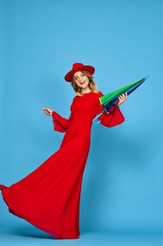 woman in red dress multicolored umbrella blue background. High quality photo