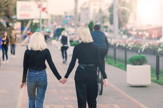 Two young females walking smiling embracing and kissing outdoor