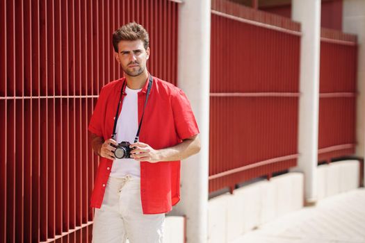 Millennial man traveling with a SLR camera outdoors