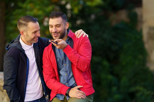 Gay couple recording a voice note together on their smartphone. Homosexual relationship concept.