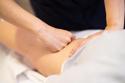 Medical massage at the leg in a physiotherapy center. Female physiotherapist inspecting her patient.