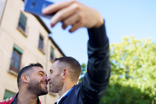Gay couple making a selfie with their smartphone. Homosexual relationship concept.
