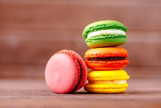 Stack of colorful macarons dessert on a wooden background.