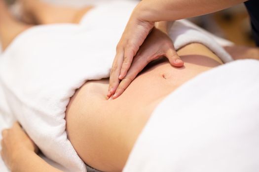 Woman receiving a belly massage in a physiotherapy center. Female patient is receiving treatment by professional osteopathy therapist.