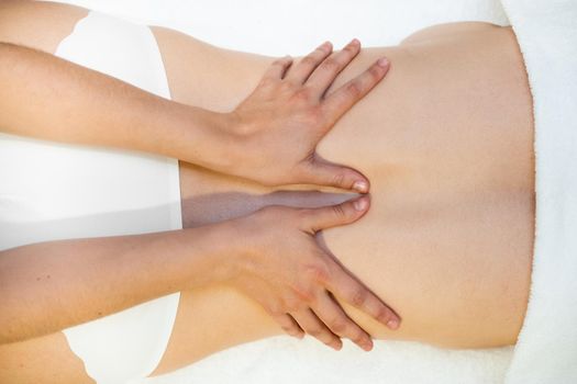 Top view of woman receiving a back massage in a spa center. Female patient is receiving treatment by professional therapist.