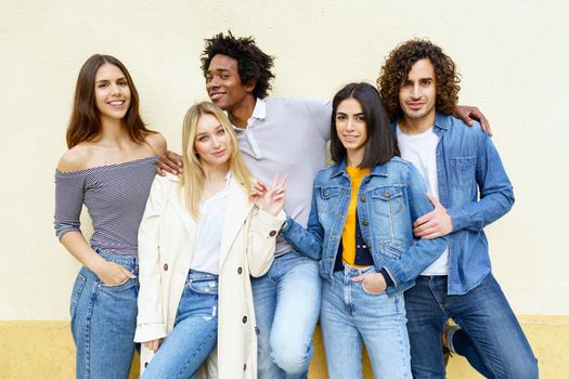 Young people having fun together. Multi-ethnic group of friends gathered in the street leaning on a railing.