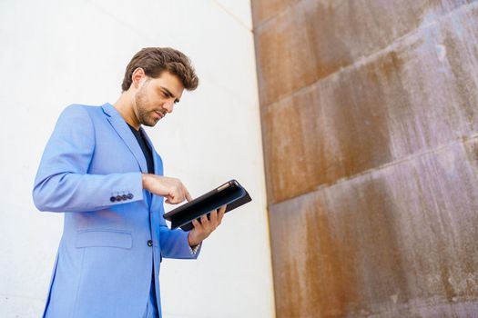 Young businessman using a digital tablet near an office building