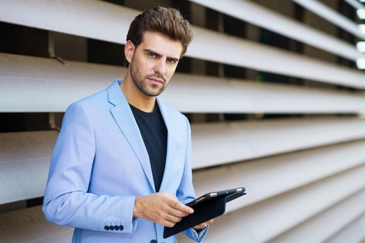 Man in a suit using a digital tablet outdoors