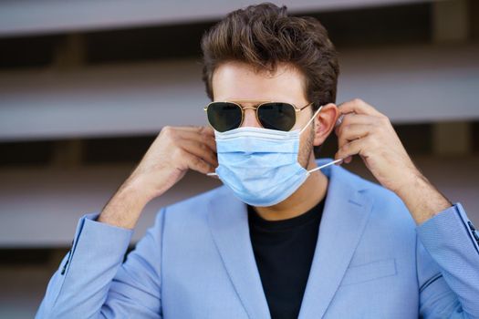 Caucasian businessman putting on a surgical mask to protect against the coronavirus.