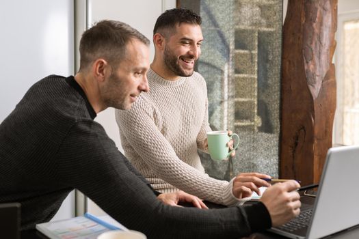 Gay couple working together at home with their laptops. Lifestyle concept.