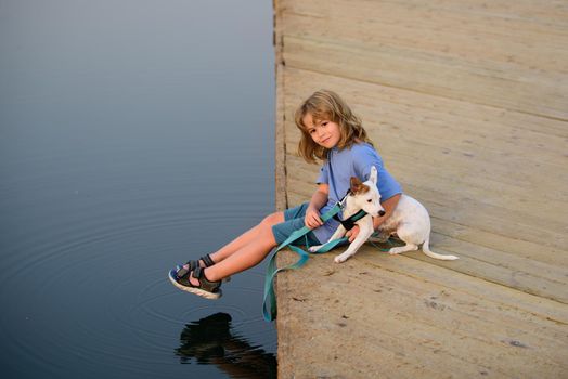 Child dreaming. Happy kid in the park with dog by the lake