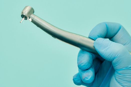 a dentist wearing gloves in the dental office holds a tool before working.