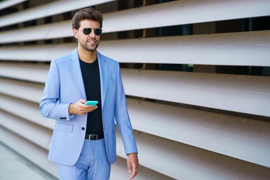 Young man walking down the street using his smartphone