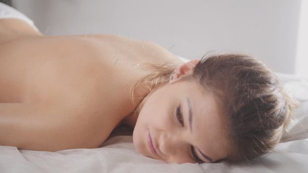 Young female relaxing in spa salon before oil sesame massage, close up