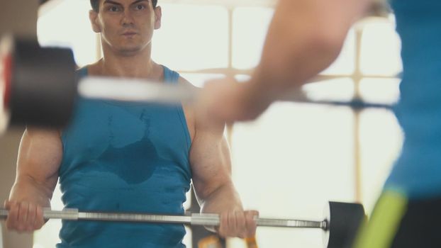 Bodybuilding in the gym - muscular man training his biceps near mirror, close up