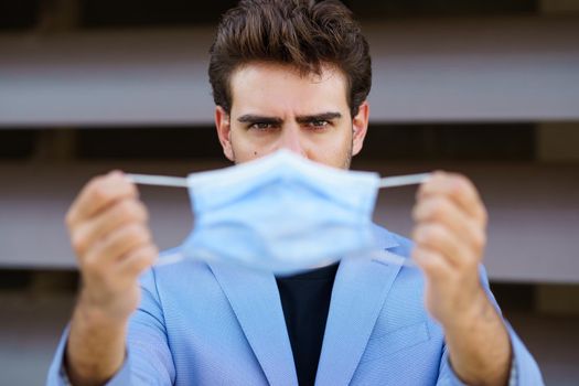 Caucasian businessman putting on a surgical mask to protect against the coronavirus.