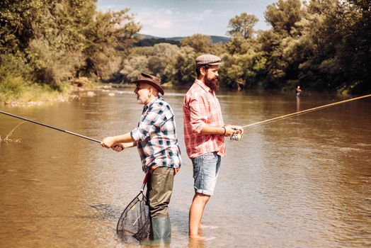 Fishermen with fishing rods in hats. Perfect weekend. Successful catch. Catch me if you can. Fisherman show fishing technique use rod. Handsome man relaxing. Having a good time