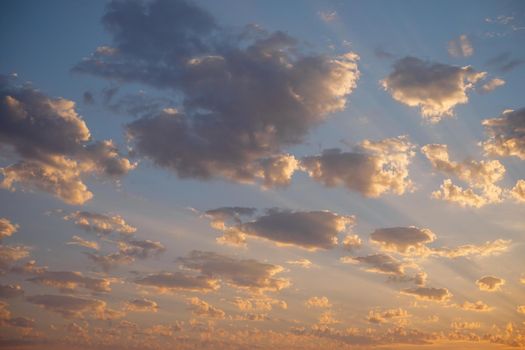 Beautiful sky background, sunset with sunbeams among small clouds.