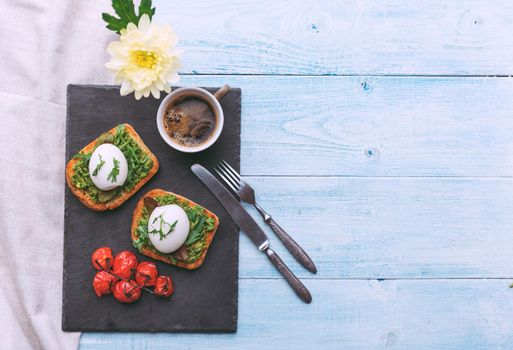 Breakfast with egg poached on avocado paddle and basil and a cup of coffee